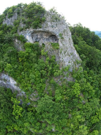Aussichtspunkt über den Bergen einer Höhle, erodiert in einer Kalkklippe an einem steilen Berghang. Der Tunnel hat Steinwände, die mit Moos bedeckt sind. Die Bögen in der Höhle werden von einer Säule gelöst. Karpathien