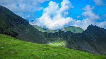 Vue sur les crêtes de Fagaras. Ciel dramatique avec nuages et brouillard recouvrant les crêtes escarpées et rocheuses de la montagne. Saison estivale, Carpathie, Roumanie.