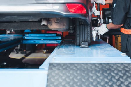In der Werkstatt der Tankstelle steht ein Auto auf einem Ständer, dessen Sensoren an den Rädern auf Achsvermessung und Sturz überprüft werden.
