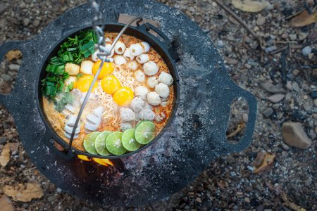 Téléchargez les photos : Nouilles instantanées dans le style coréen, Ramyeon, servi dans un pot de nouilles coréen traditionnel avec jaune d'oeuf, piment, légumes marinés et cornichons de radis. - en image libre de droit