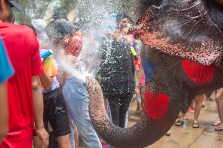 Téléchargez les photos : Un éléphant joyeux pulvérise de l'eau sur une foule lors d'une fête de l'eau colorée - en image libre de droit