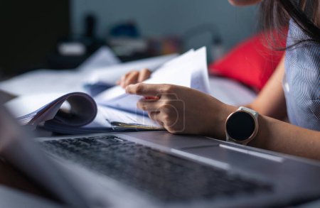 Close-up of a busy professional sorting through extensive paperwork with a smartwatch visible
