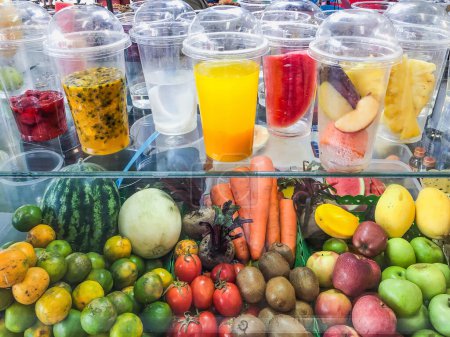 Téléchargez les photos : Affichage coloré de fruits frais et de jus de fruits prêts à boire dans des tasses en plastique transparent, favorisant des choix de mode de vie sains - en image libre de droit