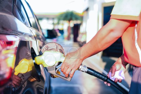 Person pumpt an einem sonnigen Tag Benzin in Auto an einer Tankstelle