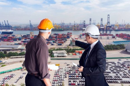 Zwei Ingenieure mit harten Hüten analysieren und diskutieren Logistik über einen geschäftigen Hintergrund in einem Schiffshafen