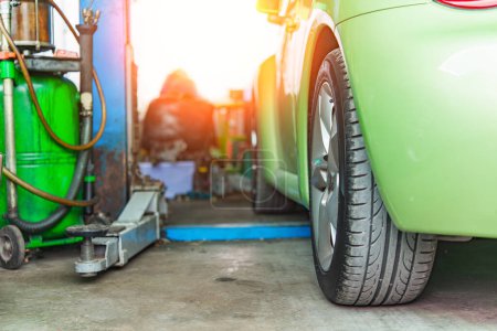 Foto de Vista de cerca de un coche verde lleno de combustible en una gasolinera, destacando el neumático y la bomba - Imagen libre de derechos