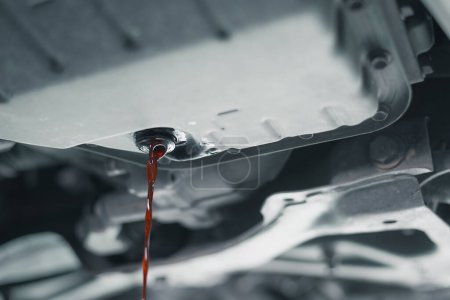 Nahaufnahme von Motoröl, das während eines routinemäßigen Ölwechsels aus einem Auto ausgetreten ist