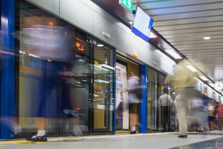 Les navetteurs en mouvement rapide se précipitent dans et hors d'un train de métro à une station urbaine moderne