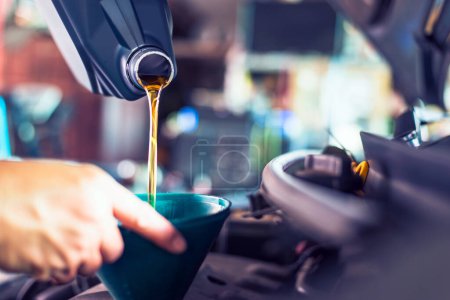 Nahaufnahme eines Mechanikers, der während einer Routinewartung frisches Öl in einen Automotor gießt.