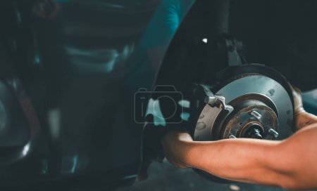 Un mecánico está cambiando el disco de freno de un coche, lo que ilustra la precisión y las habilidades de reparación de automóviles.