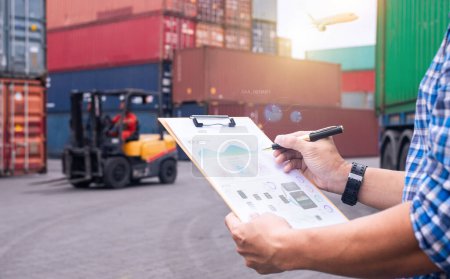 Logistics manager reviewing documents at a shipping yard, with a forklift and cargo containers in the background.