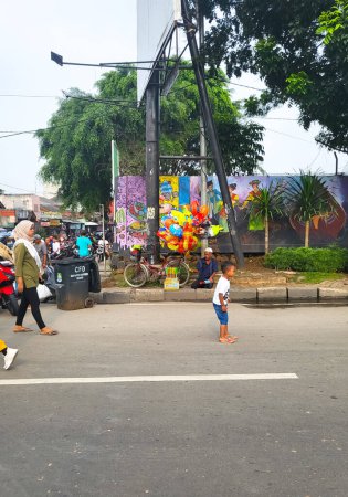 Téléchargez les photos : Bekasi, Indonésie - 12 mars 2023 : Un homme vend des ballons et des bulles de savon lors de l'événement de la journée sans voiture Bekasi - en image libre de droit