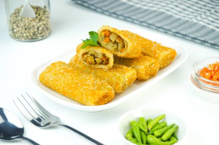 Téléchargez les photos : Risoles de légumes, en Indonésie connu sous le nom Risoles sayur. C'est comme une petite croquette remplie de carotte, roulée dans de la chapelure puis frite dans une assiette sur fond blanc. Gros plan - en image libre de droit