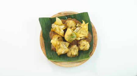 Téléchargez les photos : Le bakso frit et le tofu ou Batagor est un aliment traditionnel indonésien composé de boulettes d'assaisonnement de tapioca de poisson sauce épicée aux arachides servie dans une assiette isolée sur un fond blanc vif. Vue du dessus - en image libre de droit