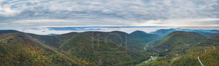 Photo for Panoramic view of the mountains covered with forests in the autumn aura. Autumn over the mountains with a thick morning fog in the background. A winding mountain road. In the vicinity of Mirmande - Royalty Free Image