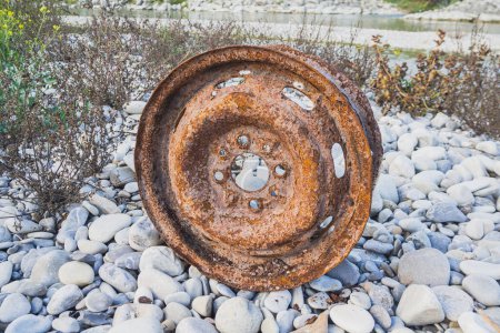 Photo for Old car wheel, rusty car alloy rim on stones by the river - Royalty Free Image