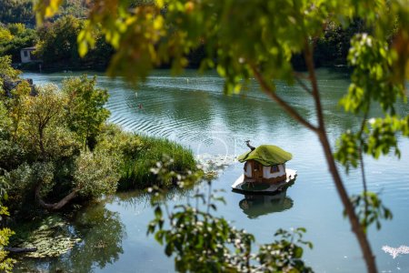 Téléchargez les photos : Un beau paysage de petite maison dans un lac dans le parc d'or Zlaten parc à Lukovit, Bulgarie. Le canard nage dans le lac. Photo de haute qualité - en image libre de droit