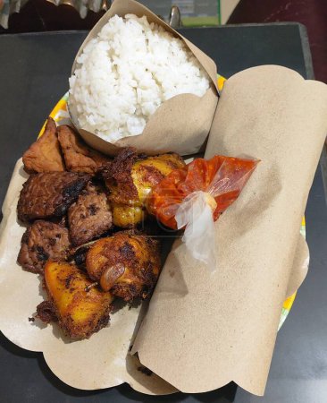 Traditional food from Indonesia, rice white grilled meat fried plantains traditional dish wrapped in banana leaves red sauce indonesian cuisine culinary