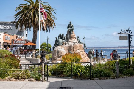 Téléchargez les photos : Monterey, États-Unis, 20 septembre 2022. Vue de la rangée de conserveries Monument avec des sculptures humaines en bronze sur les rochers à la côte de la baie de Monterey avec ciel bleu en arrière-plan pendant la journée ensoleillée - en image libre de droit