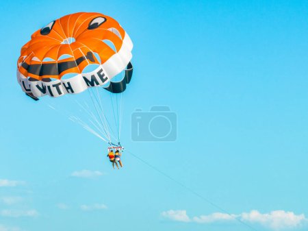 Photo for Parasailing - active form of recreation, in which a person is fixed with a long rope to a moving boat and thanks to presence of special parachute hovers through the air - Royalty Free Image