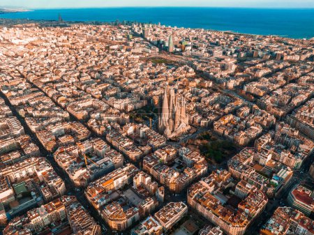 Aerial view of Barcelona City Skyline and Sagrada Familia Cathedral at sunset. Eixample residential famous urban grid. Cityscape with typical urban octagon blocks