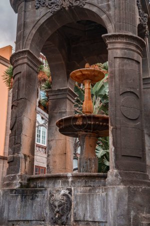 Foto de Outdoor fountain with medieval architectural structure seen through concrete arch at Plaza del Espiritu Santo in Vegueta, Las Palmas, Gran Canaria, Spain - Imagen libre de derechos