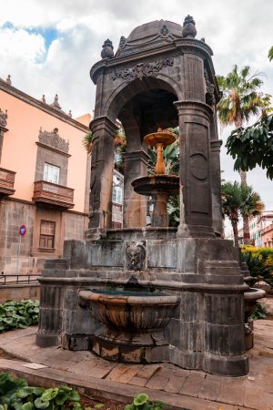Foto de Low angle view of fountain with medieval architectural structure and old building at Plaza del Espiritu Santo in Vegueta on a cloudy day at Las Palmas, Gran Canaria, Spain - Imagen libre de derechos
