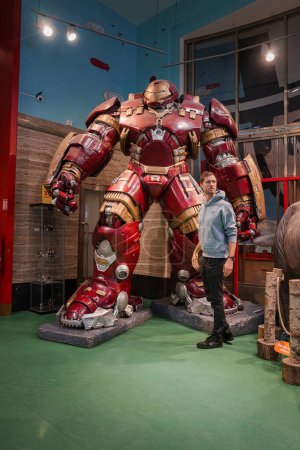 Photo for Young man standing next to the Hulk Buster Iron Man costume at The Madame Tussauds museum in Las Vegas, USA. - Royalty Free Image
