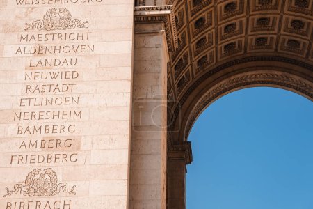 Foto de Arco de Triunfo de piedra blanca de estilo neoclásico en París, sirviendo como monumento conmemorativo con nombres de generales franceses y victorias. - Imagen libre de derechos