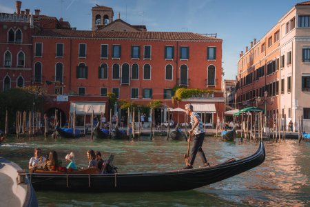 Photo for A serene black gondola floats on the Grand Canal in Venice, Italy, with another gondola in the background. The popular tourist destination offers a picturesque view for visitors and locals. - Royalty Free Image