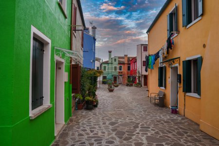 Photo for Explore the lively streets of Burano, Italy with this vibrant scene. Colorful buildings line the cobblestone street, capturing the charming essence of this picturesque Venetian-style island. - Royalty Free Image