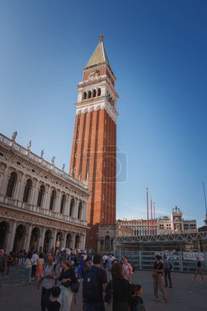 Photo for Group of people standing in front of the San Marco clock tower in Venice, Italy, a classic example of Renaissance architecture and a popular tourist attraction in the city. - Royalty Free Image