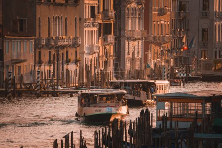 Foto de Disfrute de la tranquila belleza de Venecia al atardecer con esta impresionante imagen del Gran Canal. El cálido resplandor del sol poniente crea una atmósfera serena sobre la icónica arquitectura veneciana. - Imagen libre de derechos