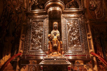 Téléchargez les photos : Une Vierge d'or Marie et Christ Enfant statue, les deux avec des halos radieux et une couronne royale, sont assis dans un sanctuaire en argent orné de reliefs bibliques, situé dans une église historique de Barcelone - en image libre de droit