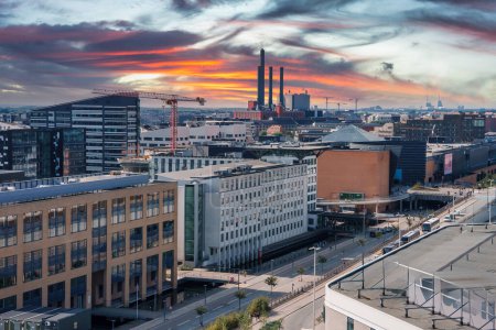 Photo for Capturing a Scandinavian cityscape at sunrise or sunset, this image features modern buildings with a mix of designs, construction cranes, and industrial chimneys in Copenhagen. - Royalty Free Image