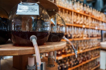 Téléchargez les photos : Gros plan d'un grand distributeur de vin en verre à la rose italienne, étiqueté Italiensk Rose, dans une boutique avec un fond flou de bouteilles, probablement à Copenhague. - en image libre de droit