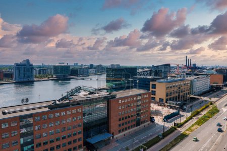 Photo for Panoramic view of a serene urban waterfront with modern buildings, reflecting a partly cloudy sky at sunset. No vehicles or boats visible, suggesting tranquility. Likely in Copenhagen or Malmo. - Royalty Free Image