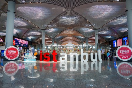 Foto de Dentro del aeropuerto de Estambul, una moderna terminal con un techo alto y ondulado y Estambul en letras rojas en el suelo, que refleja el diseño galardonado y eficiente de los aeropuertos. - Imagen libre de derechos