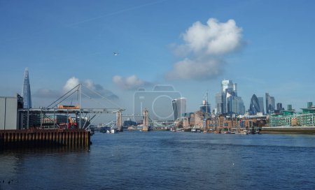 Photo for Panoramic view of the River Thames with the London skyline, featuring the Shard, Tower Bridge, and modern skyscrapers under a clear blue sky. No signs of activity or holiday decor. - Royalty Free Image