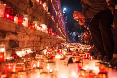 Téléchargez les photos : Un rassemblement solennel en Lettonie, avec des bougeoirs rouges illuminant la scène, signifie une commémoration respectueuse de la fête de l'indépendance, tandis que les gens en tenue chaude ajoutent à l'hommage lumineux. - en image libre de droit