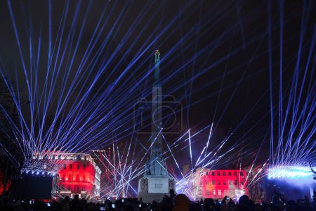Téléchargez les photos : Un spectacle de lumière laser éclaire le monument de la liberté à Riga, en Lettonie, avec des rayons bleus et rouges contre le ciel nocturne, célébrant la fête de l'indépendance de Lettonie. - en image libre de droit