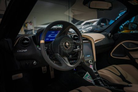 Photo for Inside a McLaren 765LT, the image showcases a sporty steering wheel with the McLaren logo, control buttons, and a digital dashboard display. A twotone interior and hightech center console add luxury. - Royalty Free Image