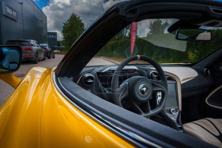 Photo for View from the drivers side into a yellow McLaren 765LTs luxurious interior, featuring a leatherwrapped steering wheel with beige stitching, and a hightech console. - Royalty Free Image