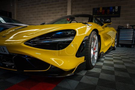 Téléchargez les photos : Une McLaren 765LT jaune élégant étoiles dans un garage chic tuning, sa construction aérodynamique mis en évidence par une vue basse et inclinée. Le plancher brillant et le réglage expert améliorent l'attrait de performance des voitures. - en image libre de droit