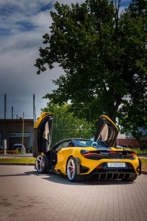 Téléchargez les photos : Une McLaren 765LT jaune vif, aux portes dièdres ouvertes, est exposée à l'extérieur. Les détails noirs accentuent son look sportif. Le dos a des feux arrière circulaires et un échappement quad. - en image libre de droit