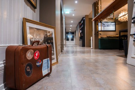 Photo for Luxurious hotel hallway in Engelberg with a vintage ski scene picture, a classic suitcase, and a modern chandelier, capturing the blend of history and contemporary elegance. - Royalty Free Image