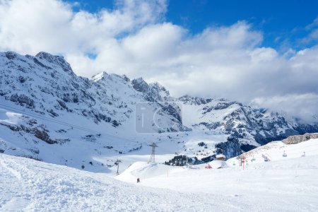 Foto de Los entusiastas de los deportes de invierno descienden las pistas en Engelberg, una estación de los Alpes suizos con montañas cubiertas de nieve, remontes y terrenos variados para todos los niveles de habilidad.. - Imagen libre de derechos