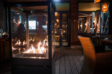 Eine luxuriöse Lounge in Engelberg mit modernem Glaskamin, Korbsesseln und eleganter Beleuchtung bietet einen warmen, einladenden Raum zum Entspannen nach dem Skifahren.