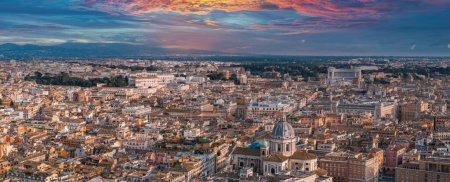 Photo for A panoramic aerial view of Rome at dusk, featuring dense historic architecture with terracotta rooftops. Domes and spires dot the skyline against a sunset painted sky in warm and cool hues. - Royalty Free Image