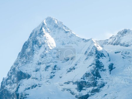 Ein majestätischer, schneebedeckter Berggipfel in den Schweizer Alpen bei Murren, in das sanfte Licht des frühen Morgens oder späten Nachmittags getaucht. Der klare Himmel und die zerklüftete Struktur unterstreichen die natürliche Schönheit der Gipfel.